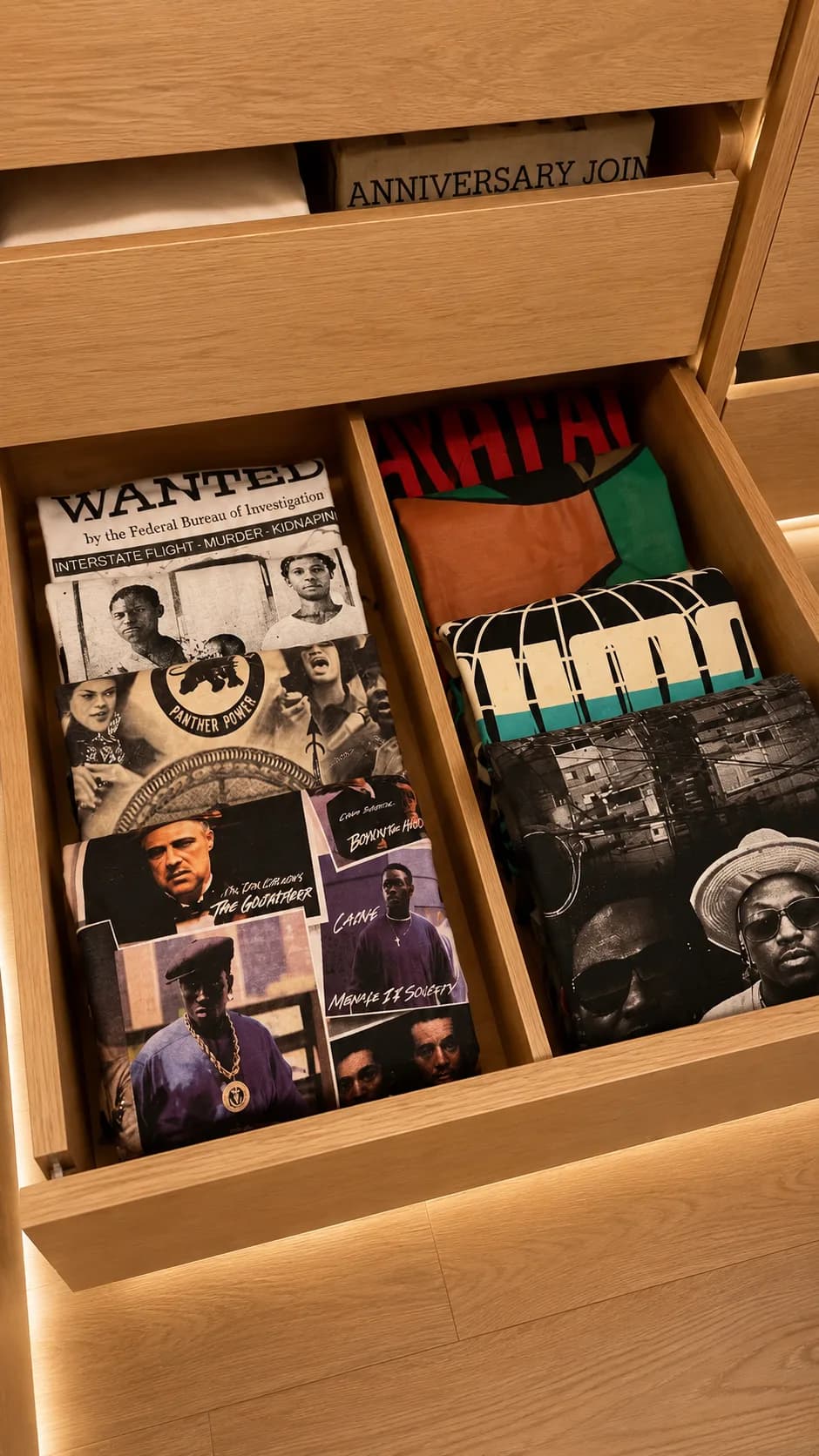 Gaveta de closet em madeira clara com camisetas estampadas dobradas na vertical, cada peça visível, Silvana Organizer